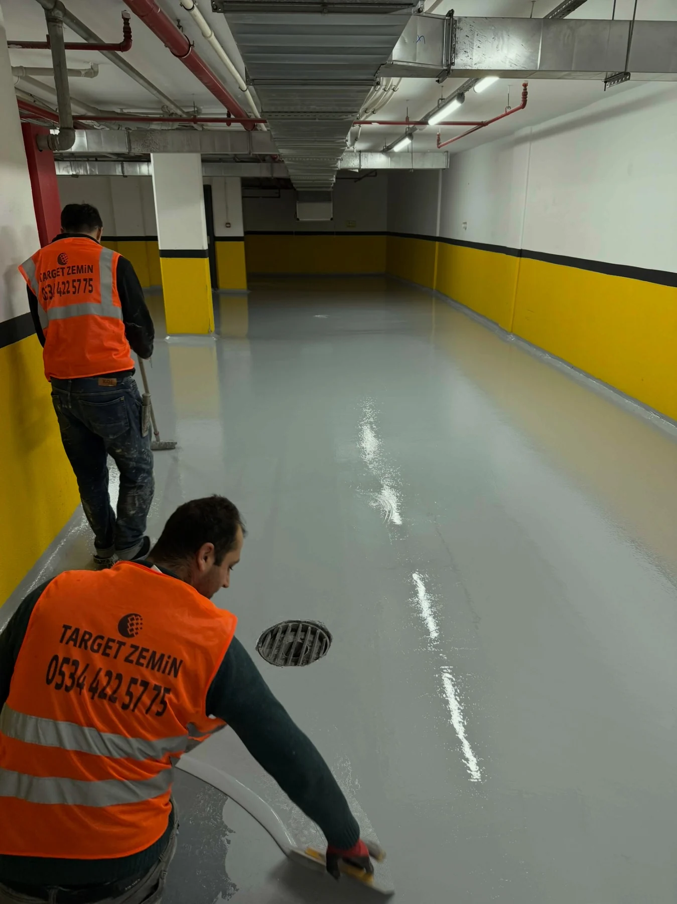 Kapalı otoparkta gri epoksi zemin kaplama uygulaması yapan ekip